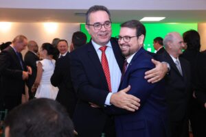 Dois homens de terno e gravata se abraçando em evento de negócios.